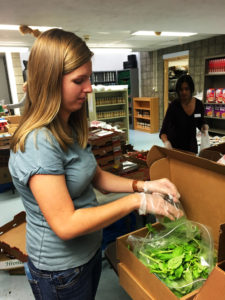 Lydia Strickling, a junior at Duquesne University and volunteer at the pantry, sorts fresh basil for distribution to community members.